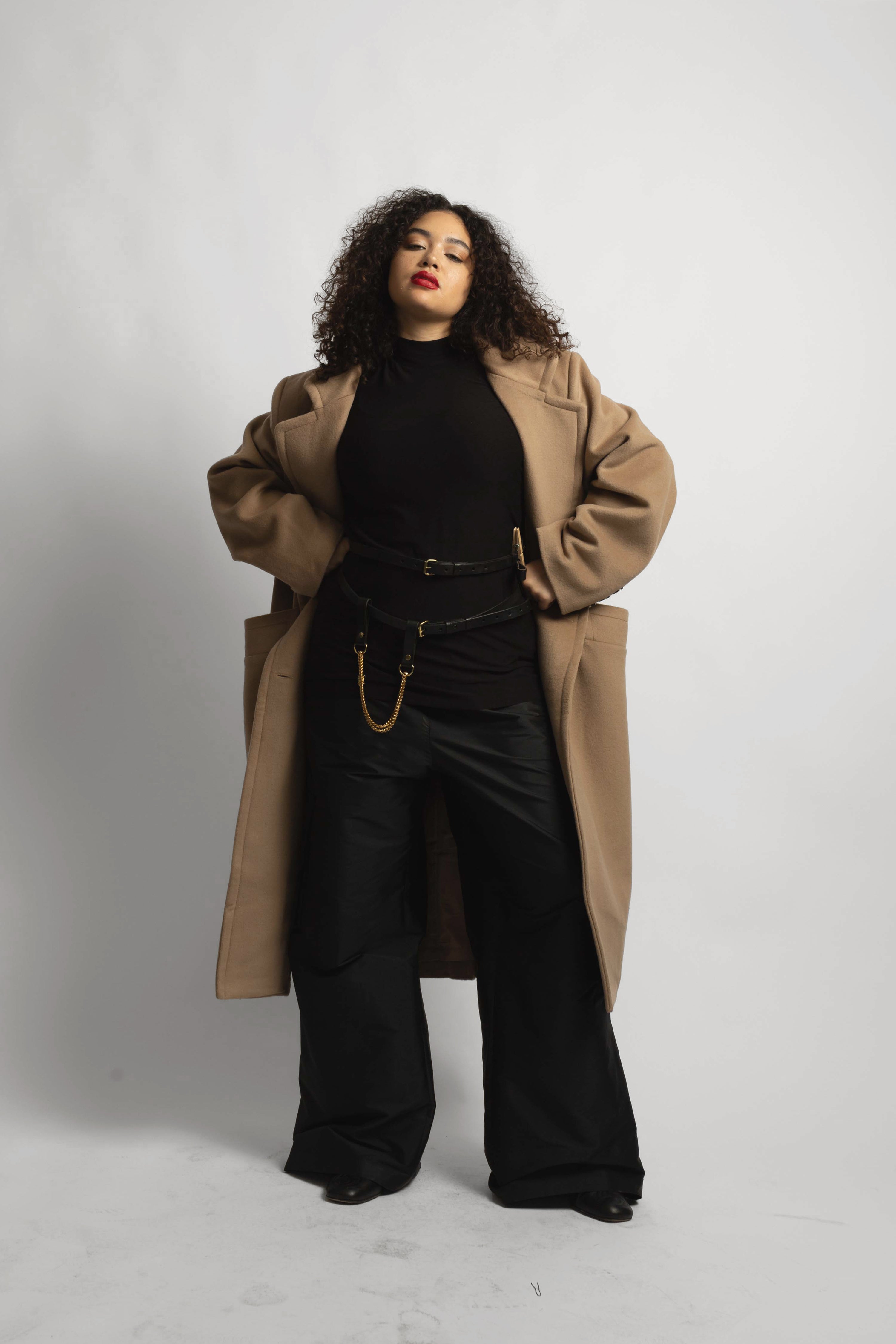 model wearing soft camel coat with hands on hips