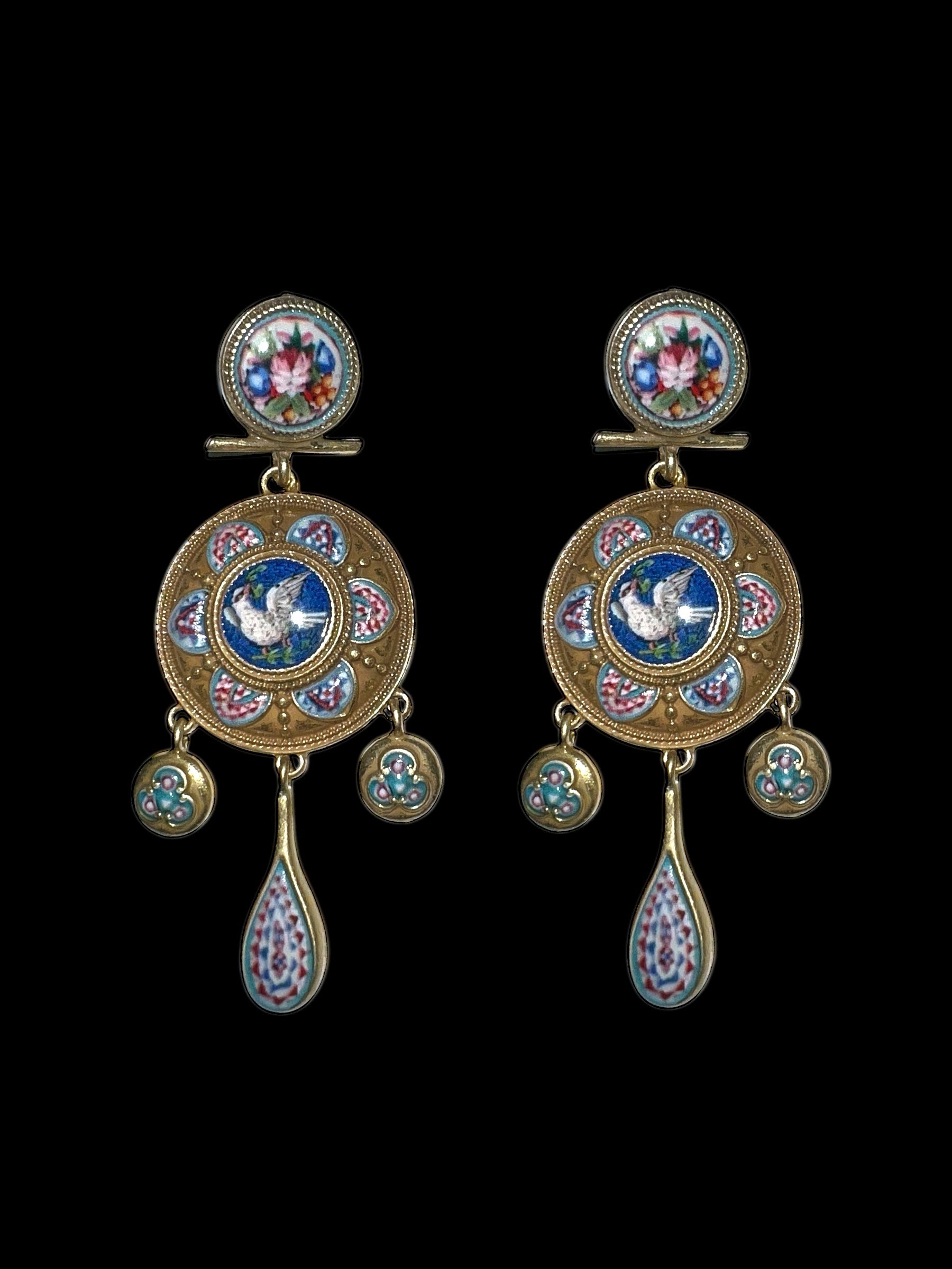 Pair of ornate earrings with intricate designs on a black background