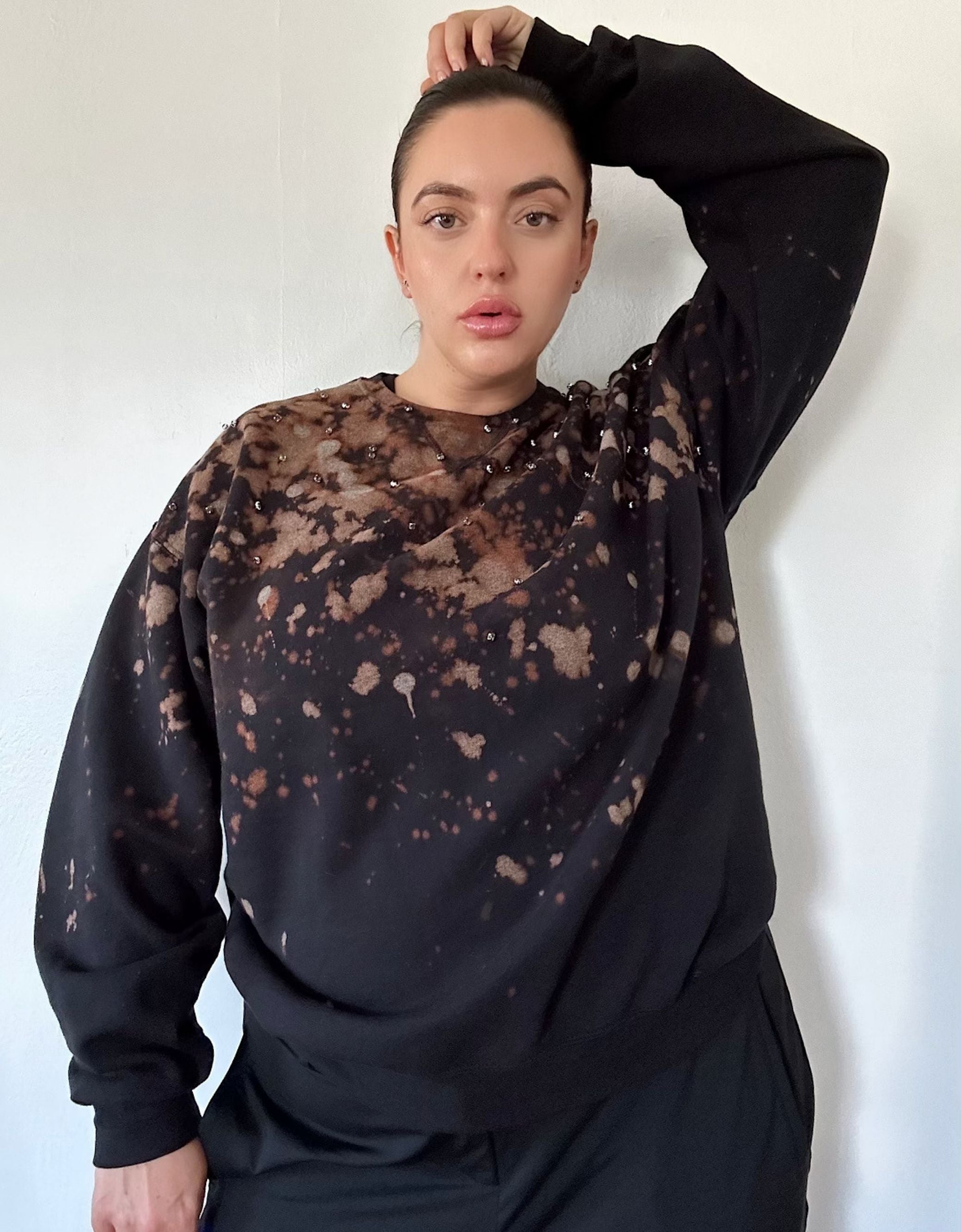 model wearing rhinestone sweatshirt with her arm up